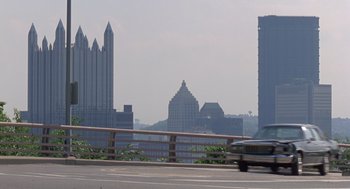 Movie still from “Striking Distance” (1993), directed by Rowdy Herrington – A car driving down a road near a city; Extreme Wide shot, Low angle