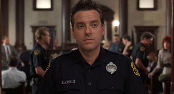 Movie still from “Striking Distance” (1993), directed by Rowdy Herrington – A man in a police uniform is looking at the camera; Close Up shot, Low angle