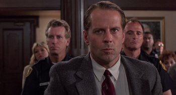 Movie still from “Striking Distance” (1993), directed by Rowdy Herrington – A man in a suit and tie in front of other men; Close Up shot, Low angle