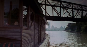 Movie still from “Striking Distance” (1993), directed by Rowdy Herrington – A boat is docked in the water under a bridge; Extreme Wide shot, High angle