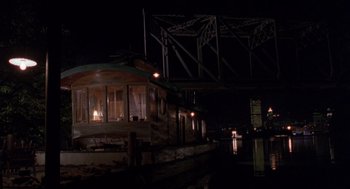 Movie still from “Striking Distance” (1993), directed by Rowdy Herrington – A boat is parked on the side of a river at night; Extreme Wide shot, High angle