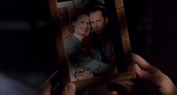 Movie still from “Striking Distance” (1993), directed by Rowdy Herrington – A person holding a picture of a man and a woman; Extreme Close Up shot, Overhead angle