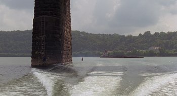 Movie still from “Striking Distance” (1993), directed by Rowdy Herrington – A person riding a boat on top of a body of water; Extreme Wide shot, Low angle