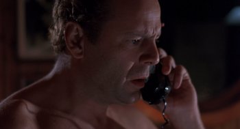 Movie still from “Striking Distance” (1993), directed by Rowdy Herrington – A man talking on a phone while sitting in bed; Close Up shot, Low angle