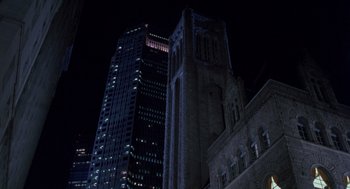 Movie still from “Striking Distance” (1993), directed by Rowdy Herrington – A tall building lit up at night in a city; Extreme Wide shot, Low angle
