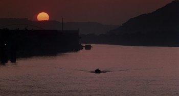 Movie still from “Striking Distance” (1993), directed by Rowdy Herrington – A boat in a body of water at sunset; Extreme Wide shot, Low angle