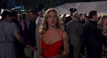 Movie still from “Striking Distance” (1993), directed by Rowdy Herrington – A woman in a red dress standing in front of a group of people; Medium shot, Over the shoulder angle
