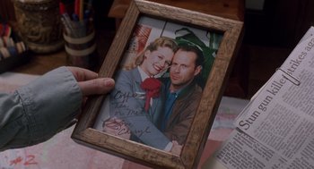 Movie still from “Striking Distance” (1993), directed by Rowdy Herrington – A person holding up a picture of a man and a woman; Extreme Close Up shot, Over the shoulder angle