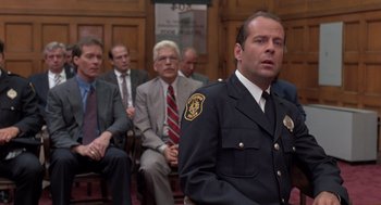 Movie still from “Striking Distance” (1993), directed by Rowdy Herrington – A man in a police officer's uniform in front of a group of men; Medium shot, Low angle
