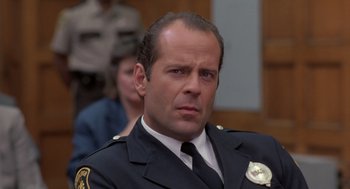 Movie still from “Striking Distance” (1993), directed by Rowdy Herrington – A man in a police uniform looks at the camera; Close Up shot, Low angle