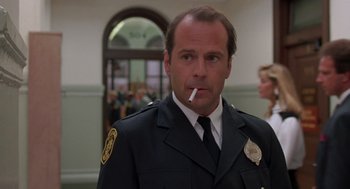 Movie still from “Striking Distance” (1993), directed by Rowdy Herrington – A police officer smoking a cigarette in front of a crowd of onlookers; Close Up shot, Low angle