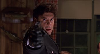 Movie still from “Striking Distance” (1993), directed by Rowdy Herrington – A man with a gun pointing at the camera; Close Up shot, Low angle