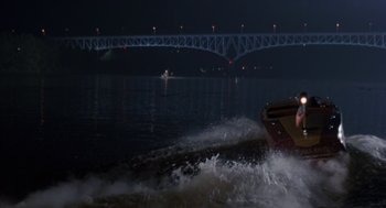 Movie still from “Striking Distance” (1993), directed by Rowdy Herrington – A speed boat in a body of water at night; Extreme Wide shot, High angle