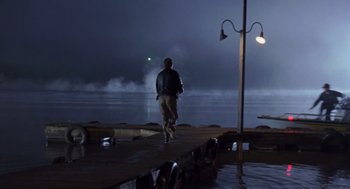 Movie still from “Striking Distance” (1993), directed by Rowdy Herrington – A man walking on a pier at night; Extreme Wide shot, Over the shoulder angle