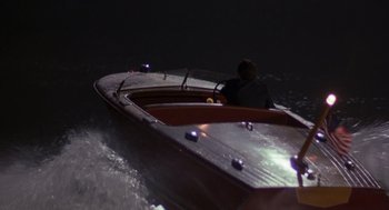 Movie still from “Striking Distance” (1993), directed by Rowdy Herrington – A man is sitting in a small boat at night; Extreme Wide shot, High angle