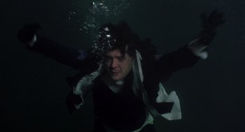 Movie still from “Striking Distance” (1993), directed by Rowdy Herrington – A man in a wet suit is submerged in the water; Medium shot, Overhead angle