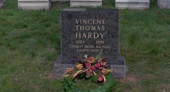 Movie still from “Striking Distance” (1993), directed by Rowdy Herrington – A grave marker with flowers on it in a cemetery; Wide shot, High angle