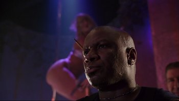 Movie still from “Striptease” (1996), directed by Andrew Bergman – A man with a knife in his mouth looking into the distance; Close Up shot, Low angle