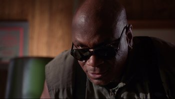 Movie still from “Striptease” (1996), directed by Andrew Bergman – A man wearing sunglasses and a jacket looking to his left; Close Up shot, Low angle