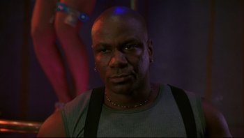 Movie still from “Striptease” (1996), directed by Andrew Bergman – A bald man with a piercing stares into the camera; Close Up shot, Low angle