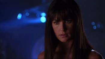 Movie still from “Striptease” (1996), directed by Andrew Bergman – A beautiful woman with long hair and bangs looking at the camera; Close Up shot, Over the shoulder angle