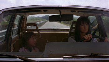 Movie still from “Striptease” (1996), directed by Andrew Bergman – Two women in the back seat of a car on a road; Medium shot, Over the shoulder angle