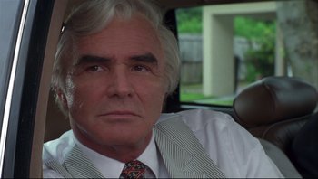 Movie still from “Striptease” (1996), directed by Andrew Bergman – An older man in a suit and tie sitting in the back of a car; Close Up shot, Low angle