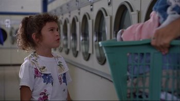 Movie still from “Striptease” (1996), directed by Andrew Bergman – A young girl is looking at a basket of laundry; Medium shot, Low angle