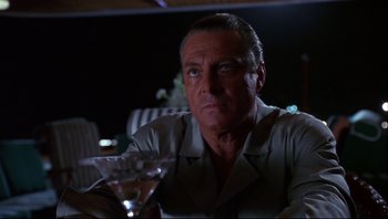 Movie still from “Striptease” (1996), directed by Andrew Bergman – A person sitting at a table with a drink; Close Up shot, Low angle