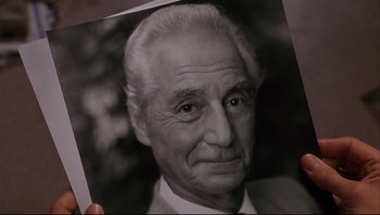 Movie still from “Striptease” (1996), directed by Andrew Bergman – An older man is holding up an old photo; Close Up shot, High angle
