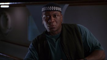 Movie still from “Striptease” (1996), directed by Andrew Bergman – A man wearing a black hat and a green shirt; Close Up shot, Low angle