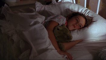 Movie still from “Striptease” (1996), directed by Andrew Bergman – A little girl laying in bed with a teddy bear; Close Up shot, High angle