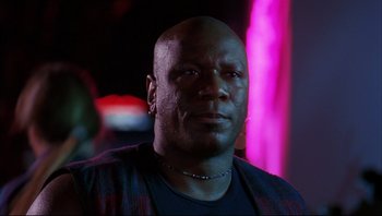Movie still from “Striptease” (1996), directed by Andrew Bergman – A bald man with a piercing is looking at the camera; Close Up shot, Low angle