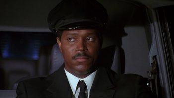 Movie still from “Striptease” (1996), directed by Andrew Bergman – A man in a suit and a hat is looking at the camera; Close Up shot, Low angle