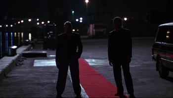 Movie still from “Striptease” (1996), directed by Andrew Bergman – Two men standing next to each other on a red carpet at night; Wide shot, Low angle