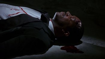 Movie still from “Striptease” (1996), directed by Andrew Bergman – A man in a suit and tie laying on the ground with blood on his face; Close Up shot, Overhead angle