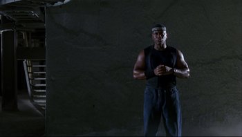Movie still from “Striptease” (1996), directed by Andrew Bergman – A man standing in front of a rock wall; Medium shot, Low angle