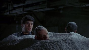 Movie still from “Striptease” (1996), directed by Andrew Bergman – A group of men standing next to each other in a room; Medium shot, High angle