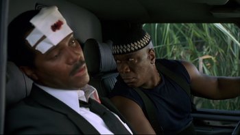 Movie still from “Striptease” (1996), directed by Andrew Bergman – Two men sitting in the back seat of a car; Close Up shot, High angle