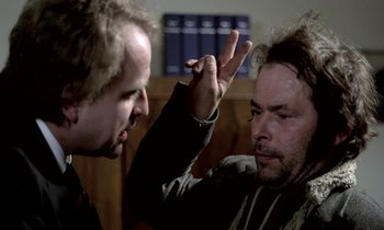 Movie still from “Stroszek” (1977), directed by Werner Herzog – Two men in a room one of them is holding a cigarette; Close Up shot, Over the shoulder angle