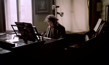 Movie still from “Stroszek” (1977), directed by Werner Herzog – A man sitting at a table in front of an easel; Medium shot, High angle