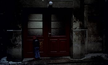 Movie still from “Stroszek” (1977), directed by Werner Herzog – A person standing in front of a red door; Wide shot, High angle