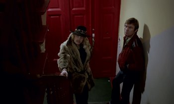 Movie still from “Stroszek” (1977), directed by Werner Herzog – A woman and a man standing in front of a red door; Wide shot, Low angle