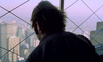 Movie still from “Stroszek” (1977), directed by Werner Herzog – A man looking out over a city from a skyscraper; Close Up shot, Over the shoulder angle
