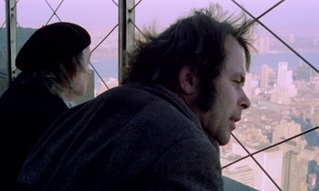Movie still from “Stroszek” (1977), directed by Werner Herzog – A man sitting on top of a building looking out at the sky; Close Up shot, Over the shoulder angle