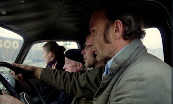 Movie still from “Stroszek” (1977), directed by Werner Herzog – A group of people riding in the back of a car; Medium shot, Over the shoulder angle