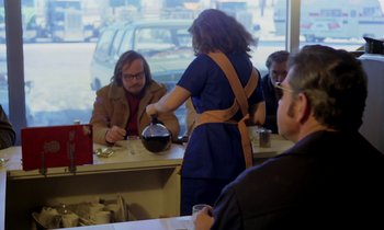 Movie still from “Stroszek” (1977), directed by Werner Herzog – A woman is pouring a drink into a cup; Medium shot, Over the shoulder angle