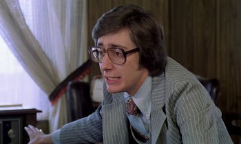 Movie still from “Stroszek” (1977), directed by Werner Herzog – A man wearing a suit and tie sitting in a room; Close Up shot, Low angle