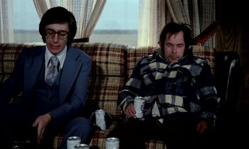 Movie still from “Stroszek” (1977), directed by Werner Herzog – Two men sitting on a couch with cans of soda; Medium shot, High angle