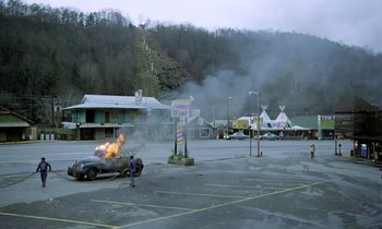 Movie still from “Stroszek” (1977), directed by Werner Herzog – A car on fire in an empty parking lot; Extreme Wide shot, High angle